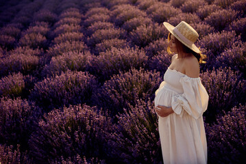 Wall Mural - the pregnant girl with a hat in the lavender field on a sunset