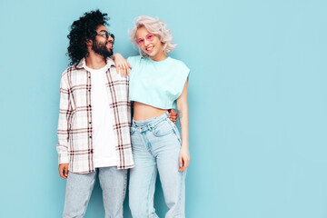 Smiling beautiful woman and her handsome boyfriend. Sexy cheerful multiracial family having tender moments on beige background in studio. Multiethnic models hugging. Embracing each other.Love concept