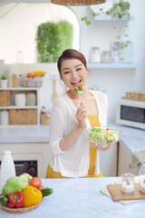 Wall Mural - Young woman eating salad and holding a mixed salad .