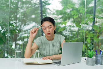 Fototapete - Young asian businesswoman holding pencil thinking and planning business strategy while sitting at office desk.