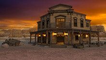 Old Wild West Saloon In A Western Desert Town At Sunset With Mountains Under Orange Sky In The Background. 3D Rendering.