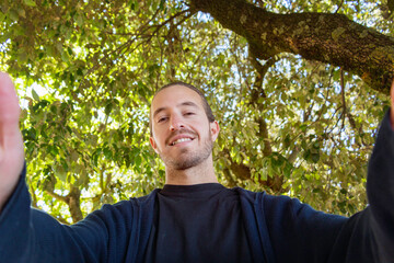 attractive young smiling and taking himself a selfie outdoor on a sunny day