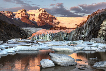 Wall Mural - Warm sunlight across the ice and mountains of Svinafellsjokul glacier at sunset., southern iceland. Part of the larger Vatnajokull glacier