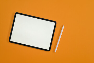 Poster - Top view with empty screen of digital tablet, tablet and stylus pen on yellow studio background.