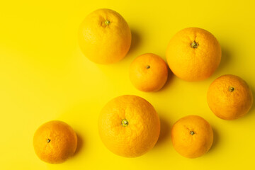 Wall Mural - Top view of fresh oranges and mandarins on yellow background.