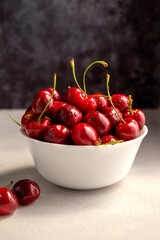 Wall Mural - Fresh red cherries in white bowl, on dark background. Summer delicious fruit.