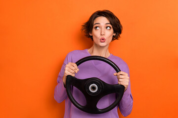 Poster - Photo of impressed shocked lady wear violet sweatshirt riding car looking empty space isolated orange color background