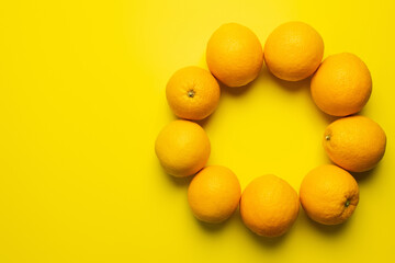 Wall Mural - Top view of oranges in frame shape on yellow background.