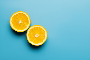 Wall Mural - Top view of cut oranges with shadow on blue background with copy space.