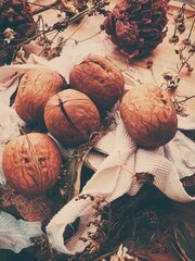 Poster - Vertical shot of nuts with dried herbs and flowers on a wooden background - autumn aesthetics