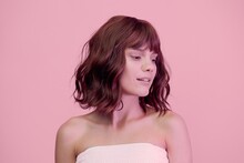 A Close Portrait Of A Sweet, Happy Woman Standing On A Pink Background With Pink Lighting From The Side, With Beautiful, Wave-styled Hair, Looking At The Bottom Of The Frame