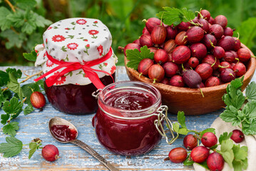 Gooseberry  jam or confiture in glass jars in a summer garden. Selective focus