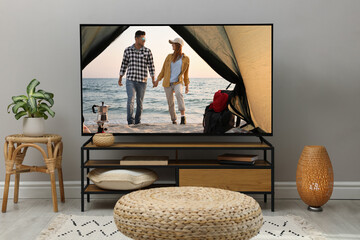 Wall Mural - Modern TV set on wooden stand in room. Scene of romantic movie on screen