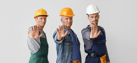 Wall Mural - Miner men showing STOP gesture on grey background