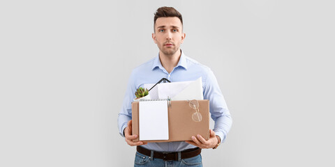 Poster - Dismissed man holding box with personal things on light background