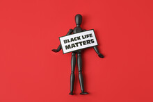 Black Mannequin And Paper Sheet With Text BLACK LIFE MATTERS On Color Background