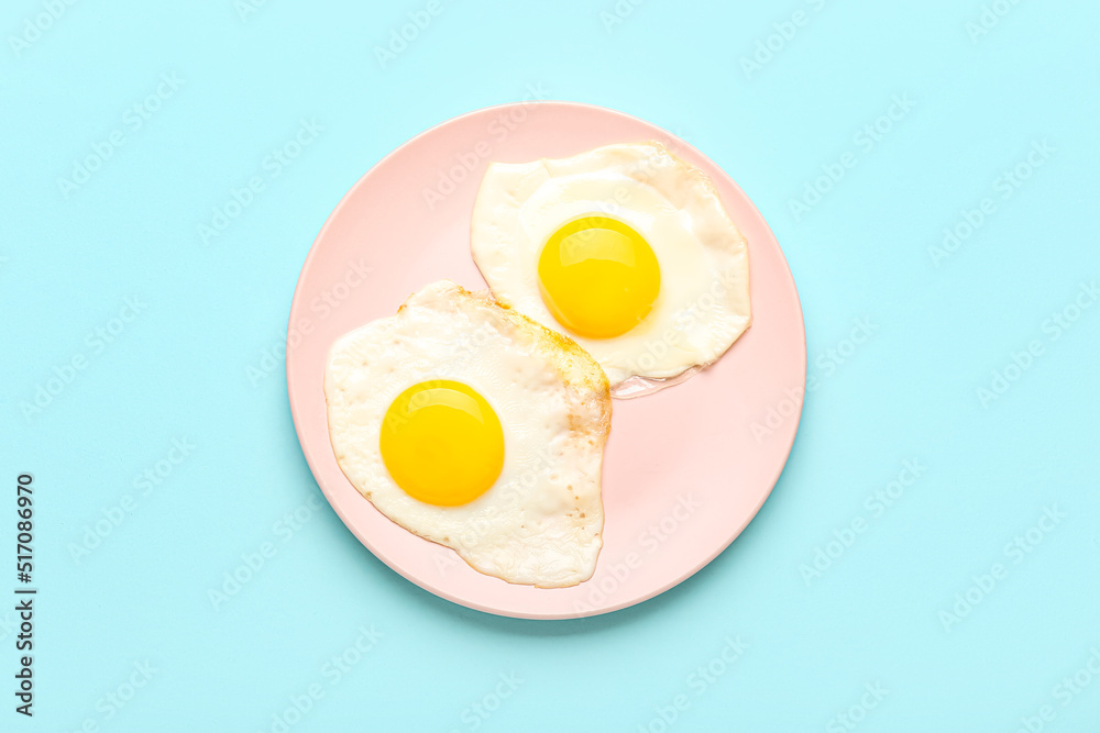 Plate with tasty fried egg on blue background