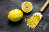 Fototapeta  - grating lemon zest Ready to Cook, Grater peel and lemon zest on dark background, banner, menu, recipe, top view
