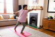 © Wavebreak Media - Biracial mature woman with arms outstretched practicing warrior 2 pose on mat in living room