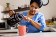© Wavebreak Media - Low angle view of biracial mature woman pouring coffee with french press in mug on kitchen island