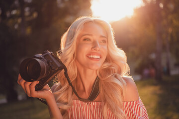 Poster - Portrait of nice cheerful person hold camera look interested away far have good mood walk outside