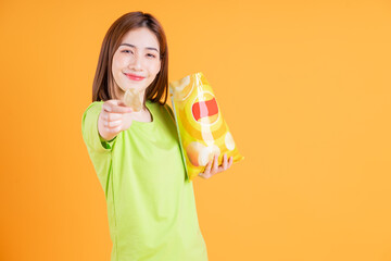 Wall Mural - Photo of young Asian girl eating snack on background