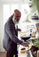 Smiling Man With Beard Cooking In Kitchen