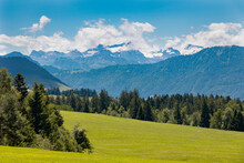 Alpine Landscape With Green Fields And Snowy Peaks
