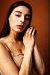 © iordani - Cute happy young indian woman on brown background in studio close up smiling, fashion beauty warm tanned