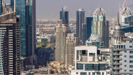 Wall Mural - Dubai Marina and Media City districts with modern skyscrapers and office buildings aerial timelapse during all day with shadows moving fast. Traffic on overpass and road intersection near green park