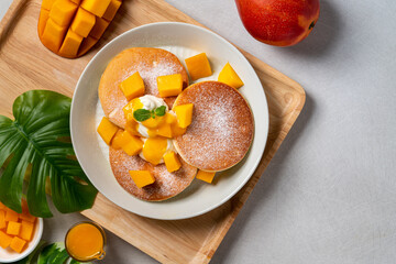 Wall Mural - Delicious Japanese souffle pancake with dice mango and jam on white table background.