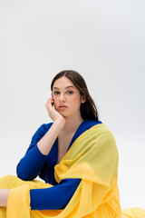 Wall Mural - pretty ukrainian young woman in blue and yellow outfit looking at camera isolated on grey.