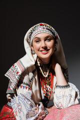 Wall Mural - portrait of happy young ukrainian woman in traditional clothing with ornament and red beads on black.