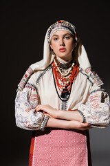 young ukrainian woman in traditional shirt with ornament and red beads posing on black.