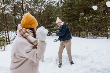 Poster - people, season and leisure concept - happy couple playing snowballs in winter park