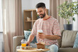 © Syda Productions - consumption, delivery and people concept - smiling man with takeaway food and drinks at home