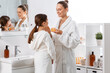 © Syda Productions - beauty, hygiene, morning and people concept - happy smiling mother and daughter with moisturizer at bathroom
