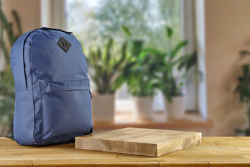 Wall Mural - Schoolbag on table and blurred window with green plants. 