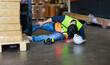 © NVB Stocker - First Aid and safety first concept. Warehouse man worker lying down on floor after accident in warehouse factory. Professional engineering teamwork. Health insurance emergency accident in workplace.