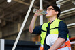 © NVB Stocker - Time for a tea break concept. Asian male warehouse Industrial, factory and energy engineer Specialist drinking water sitting on stair at warehouse office factory workplace.