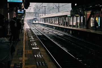 Beautiful shot of people waiting for a train at a station on a rainy day