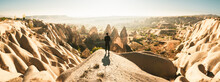 Thoughtful Female Person Stand Look Over Dramatic Valley On Hazy Morning Sunrise With Fairy Chimneys Background. Solo Exploration In Turkey. Cinematic Travel Destination-Cappadocia
