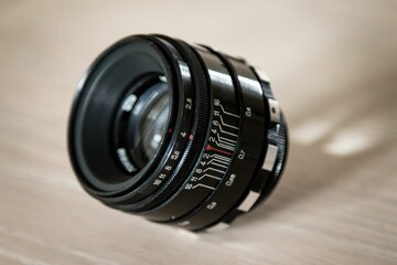 Sticker - Closeup of black camera lens on blur wooden background