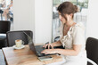 © Iris - young woman having a coffee while working with the laptop