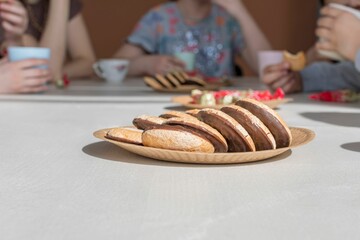 Poster - On light surface of kitchen table is brown paper plate with delicious chocolate chip cookies.