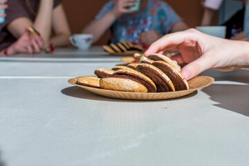 Canvas Print - On light surface of kitchen table is brown paper plate with delicious chocolate chip cookies. One ha