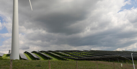 Solar Panels And Wind Turbines In Grassy Field With overcast light - Renewable Energy Concept