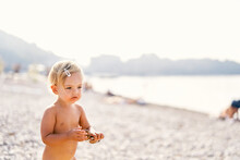 Little Girl With Sunglasses In Her Hands Stands On The Beach