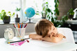 © Надежда Урюпина - Little boy doing homework at home at the table, overwork of a first-grader from studying, stress of a schoolboy, sleeps at the table