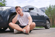 © Евгений Шемякин - Frustrated sad upset guy driver is sitting near a broken car after road accident, crash. Young shocked desperate frightened man got into traffic car accident, sitting on asphalt holding head with hand